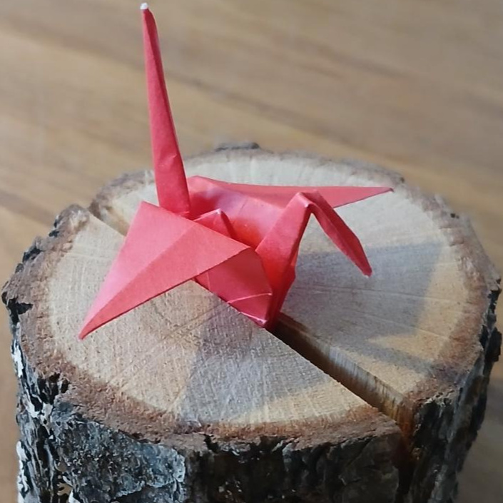 selbst gefalteter Kranich in Holzständer